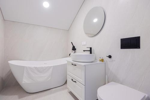 a white bathroom with a sink and a mirror at Emgus cottages (Nature & Comfort) in Palanga