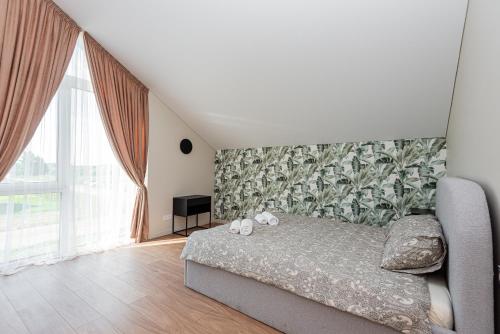 a bedroom with a bed and a large window at Emgus cottages (Nature & Comfort) in Palanga