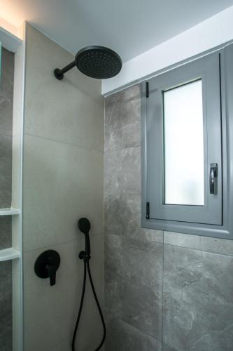 a bathroom with a shower with a window at Anemone Premium Suites Faliraki in Faliraki