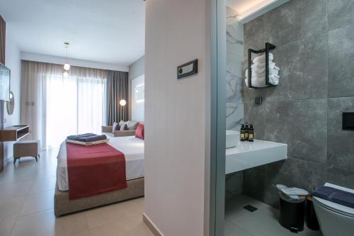 a hotel room with a bed and a bathroom at Anemone Premium Suites Faliraki in Faliraki