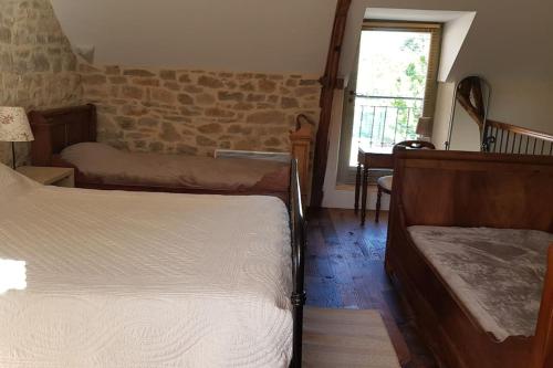 a bedroom with two beds and a brick wall at Maison de village avec piscine privative - gite-loubaribas in Condat
