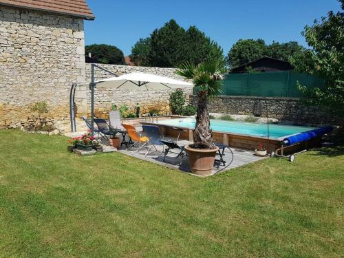 a pool with chairs and a palm tree and an umbrella at Maison de village avec piscine privative - gite-loubaribas in Condat