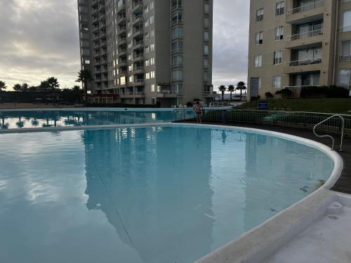 uma grande piscina de água azul em frente a alguns edifícios em RESETEATE EN FAMILIA ALGARROBO em Algarrobo