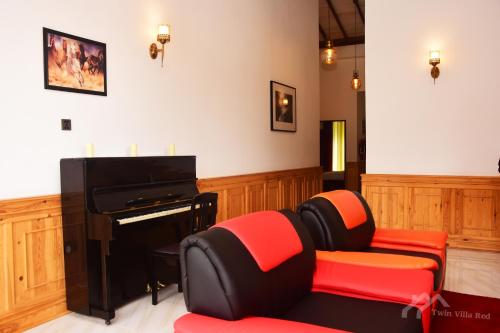 a living room with a piano and red chairs at Twin Villa Red in Nuwara Eliya
