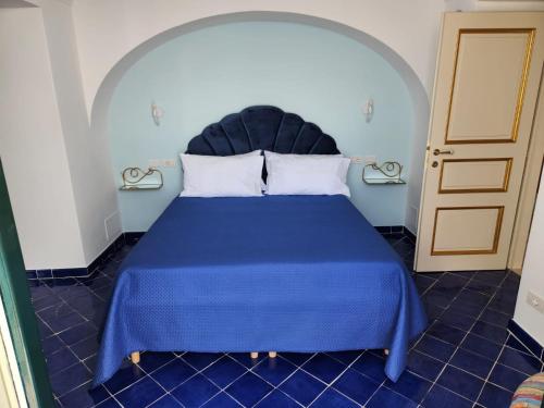 Palazzo Rocco - Golden Suite - Praiano - Amalfi Coast في برايانو: غرفة نوم بسرير ازرق مع لحاف ازرق