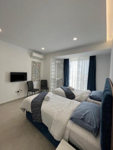 a bedroom with two beds and a flat screen tv at St Julians Penthouse in St Julian's