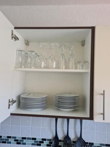 une armoire remplie de verres et d'assiettes dans la cuisine dans l'établissement Ferienwohnung Eichhörnchen, à Krefeld