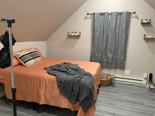 a bedroom with a bed with an orange blanket and a window at Modern Couples Retreat in Newark