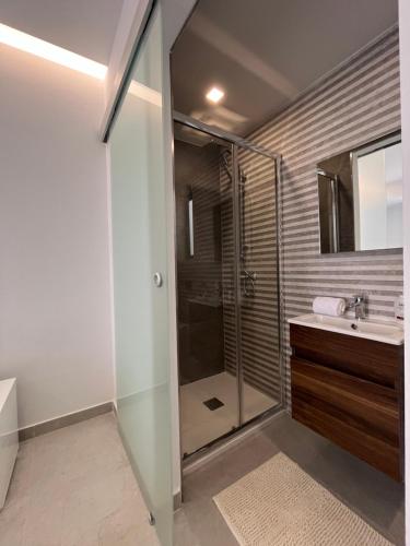 La salle de bains est pourvue d'une douche en verre et d'un lavabo. dans l'établissement St Julians Penthouse, à San Ġiljan