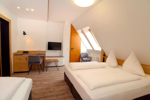 a bedroom with two beds and a desk and a television at Hotel Gasthof Krone in Spalt