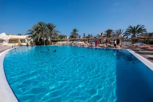 a swimming pool at a resort with palm trees at Les Quatre Saisons Ex Baya Beach in Djerba