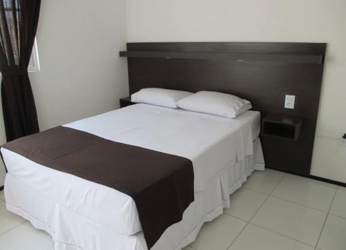a bedroom with a large white bed with a black headboard at SOL BRASIL HOTEL e POUSADA in Fortaleza