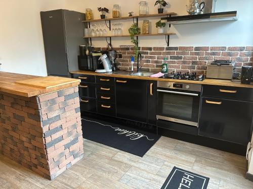 une cuisine avec des armoires noires et un mur en briques dans l'établissement La Maison de la Côte, à Boulogne-sur-Mer