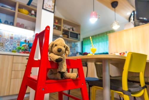 un oso de peluche sentado en una silla roja junto a una mesa en Boho House 4 in camp Terme Catez, en Čatež ob Savi