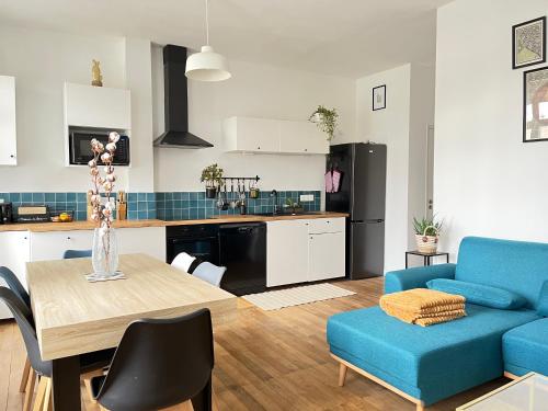 eine Küche und ein Wohnzimmer mit einem Tisch und einem blauen Sofa in der Unterkunft Cœur de Vendôme in Vendôme