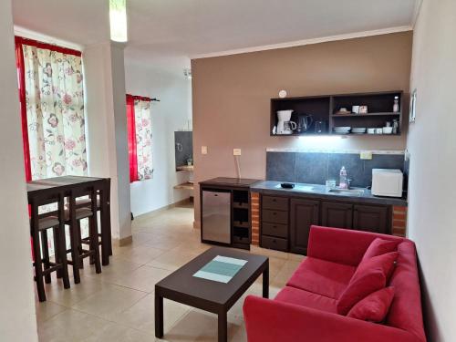 a living room with a red couch and a kitchen at Departamentos Serena in Puerto Iguazú