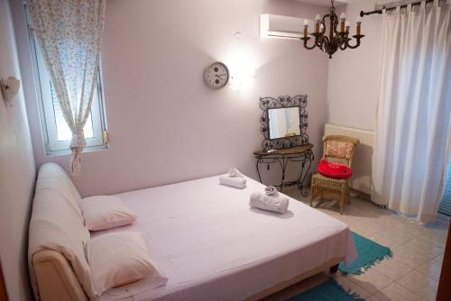 a bedroom with a white bed and a chair at The Early Bird - Cosy 2-Floor House with Garden in Alexandroupoli