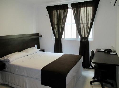 a bedroom with a bed and a desk and windows at SP Hotel Fortaleza in Fortaleza