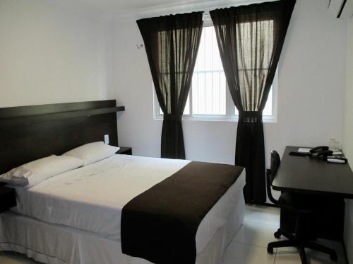 a bedroom with a bed and a desk and windows at SOL BRASIL HOTEL e POUSADA in Fortaleza