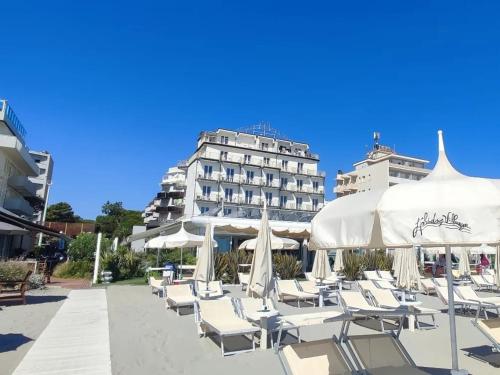 a row of chairs and umbrellas in front of a hotel at Hotel B&B Negresco in Milano Marittima