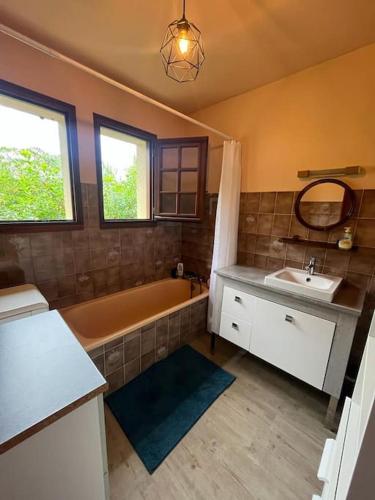 une salle de bain avec une baignoire, un lavabo et un miroir dans l'établissement Maison grand terrain 200m Plage, à Capbreton