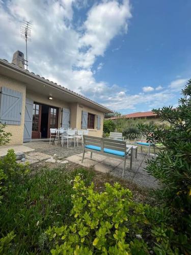 un patio avec un banc bleu et des tables devant une maison dans l'établissement Maison grand terrain 200m Plage, à Capbreton