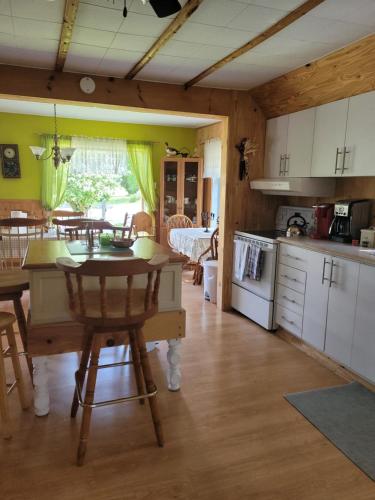 - une cuisine et une salle à manger avec une table et des chaises dans l'établissement Le Gîte Du Gardien Blanc, à Saint-David-de-Falardeau