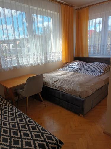 a bedroom with a bed and a desk and windows at Pokoje Przy Plaży- Morska 26 in Władysławowo