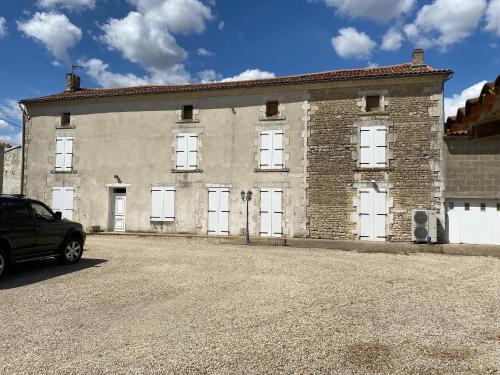 un grand bâtiment en briques avec des portes blanches dans une rue dans l'établissement Large French Farmhouse, à Néré