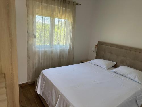 a bedroom with a white bed and a window at Niki Apartments in Ulcinj