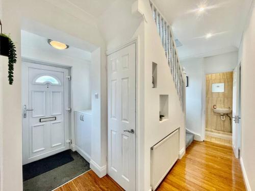 a hallway with a white door and a stair case at Modern 3 Bed Romford Home (Free Parking) in Havering atte Bower