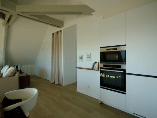 - une cuisine blanche avec une cuisinière et une chaise dans l'établissement La dunette : loft vue imprenable, à Réville
