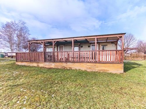 a house with a deck on a grass field at Mobilní dům U Goldy in Česká Skalice