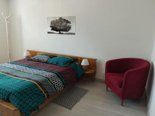 una camera da letto con un letto e una sedia rossa di Charmante maison à Corme-Royal a Corme-Royal