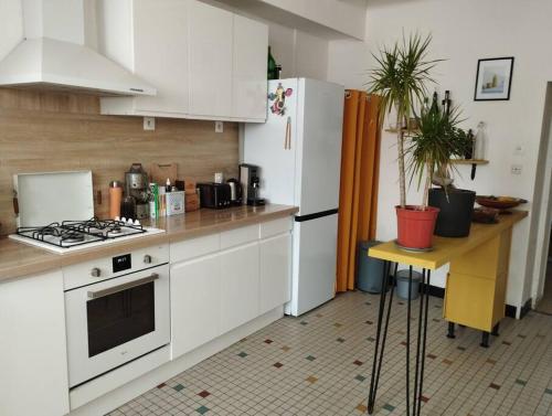 une cuisine avec des armoires blanches et un réfrigérateur blanc dans l'établissement Charmante maison à Corme-Royal, à Corme-Royal