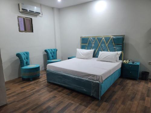 1 dormitorio con 1 cama y 2 sillas azules en Safari Hotel, en Lahore