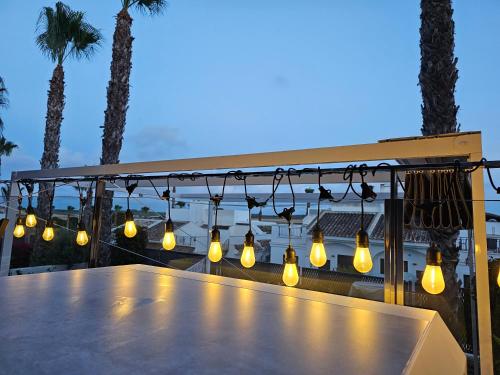 a group of lights hanging over a table with palm trees at Casa Veran at La Finca Golf in Algorfa