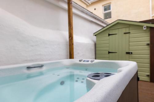 baño con bañera de hidromasaje y cobertizo verde en The Cadnant Holiday House en Llandudno