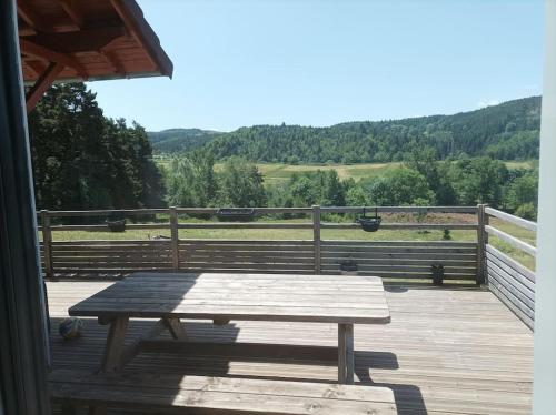 a picnic table on a deck with a view of a field at Suite à la campagne dans une jolie maison en bois. in Laussonne