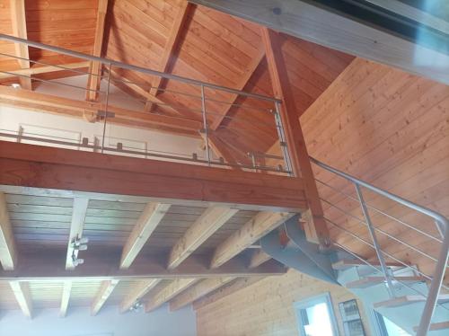 a loft bed in a room with wooden ceilings at Suite à la campagne dans une jolie maison en bois. in Laussonne