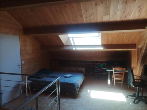 Zimmer im Dachgeschoss mit einem Bett, einem Tisch und Stühlen in der Unterkunft Suite à la campagne dans une jolie maison en bois. in Laussonne