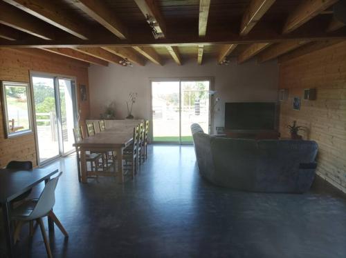 a living room with a couch and a table and chairs at Suite à la campagne dans une jolie maison en bois. in Laussonne