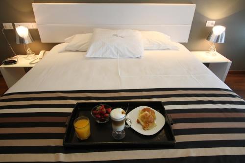 a tray of food on a bed with a plate of food at Regency Golf - Hotel Urbano in Montevideo