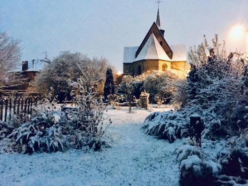 a church covered in snow in front of a yard at Aubépine in Sains-du-Nord