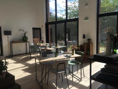 a room with tables and chairs and large windows at Aubépine in Sains-du-Nord