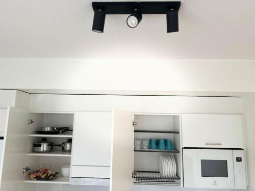 a kitchen with white cabinets and a microwave at Huoneisto juna aseman vieressä in Vantaa