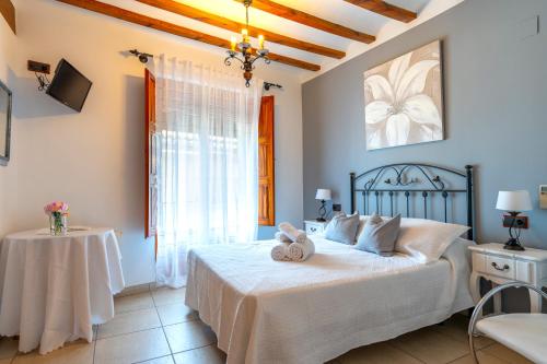 a bedroom with a bed with white sheets and a window at Hotel El Rullo in Vilafamés