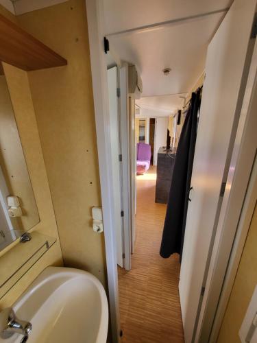 La salle de bains est pourvue d'un lavabo, de toilettes et d'un couloir. dans l'établissement Mobil home climatisé 6 personnes avec piscine, à Fréjus