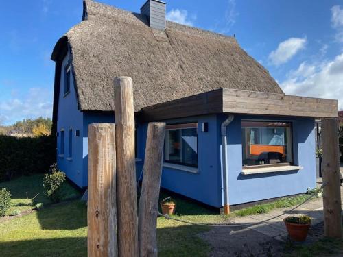 a blue house with a thatched roof at Dat Smucke Reethus Erdgeschoss in Born