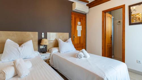 two beds in a hotel room with white sheets at Hotel El Rullo in Vilafames